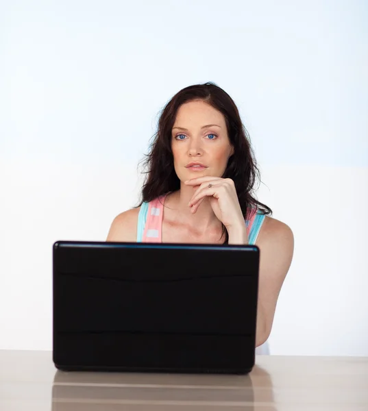 Женщина, работающая со своим ноутбуком, смотрит в камеру — стоковое фото