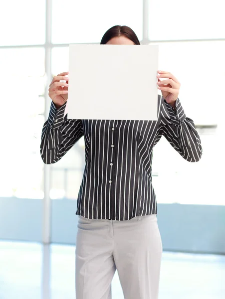 Yüzünün önünde beyaz kartı gösteren iş kadını — Stok fotoğraf