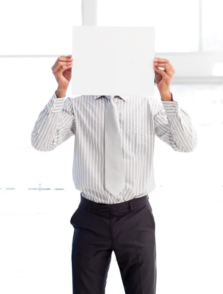 Empresario sosteniendo una tarjeta blanca cubriéndose la cara — Foto de Stock