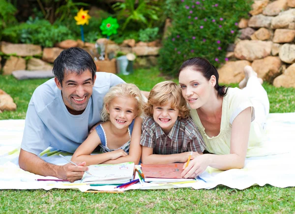 Glad familj målning i en park som ler mot kameran — Stockfoto