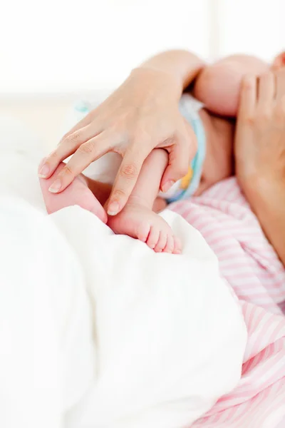 Mãos segurando um bebê recém-nascido na cama — Fotografia de Stock