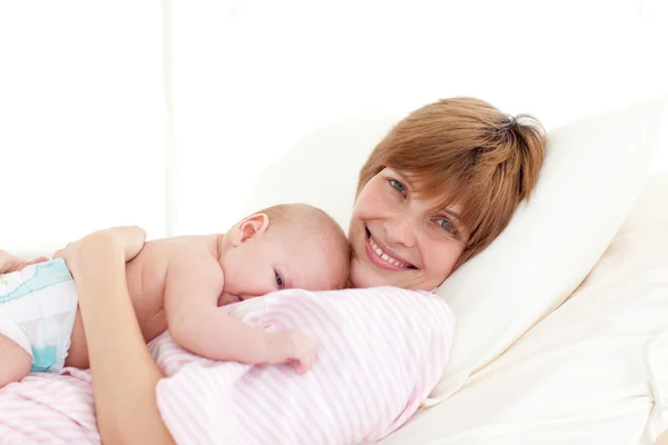 Mother with newborn baby in bed smiling at the camera — Stok fotoğraf