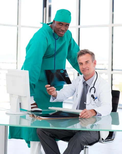 Médicos mirando a la cámara con una radiografía — Foto de Stock