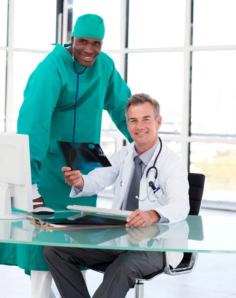 Доктор и хирург улыбаются в камеру с помощью рентгена — стоковое фото