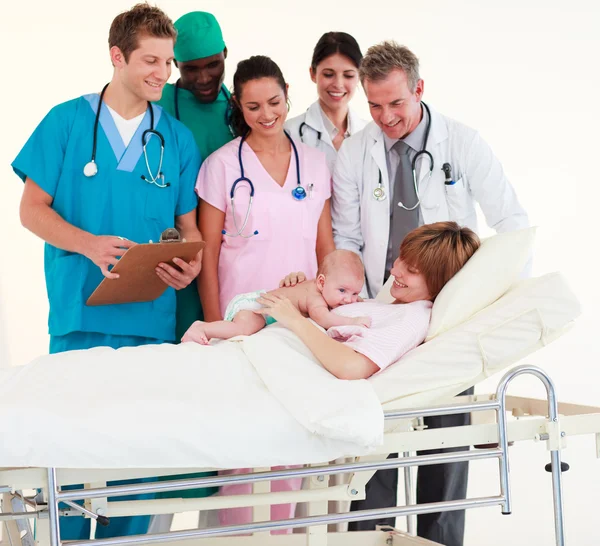 Lékaři ošetřující pacienta a novorozeně — Stock fotografie
