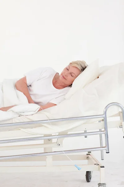 Mulher idosa relaxada deitada em uma cama — Fotografia de Stock