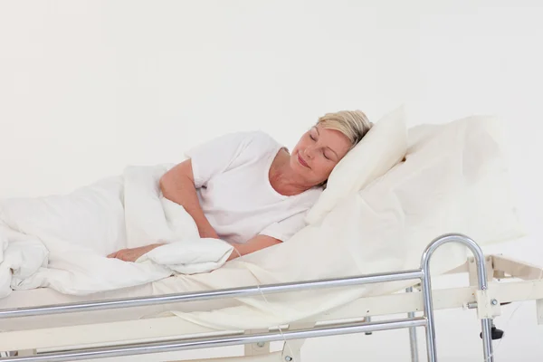 Relajada mujer mayor acostada en una cama — Foto de Stock