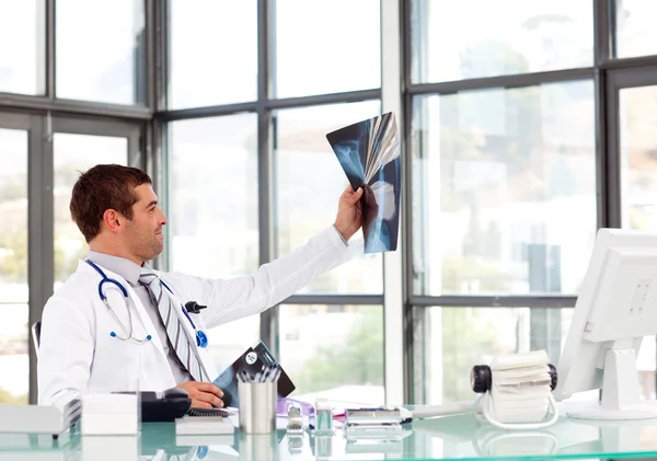 Médico varón examinando una radiografía en su escritorio —  Fotos de Stock