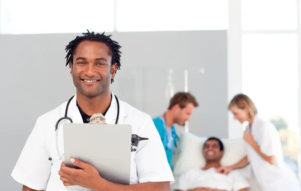 Afrikanischer Arzt mit einem Patienten im Hintergrund — Stockfoto