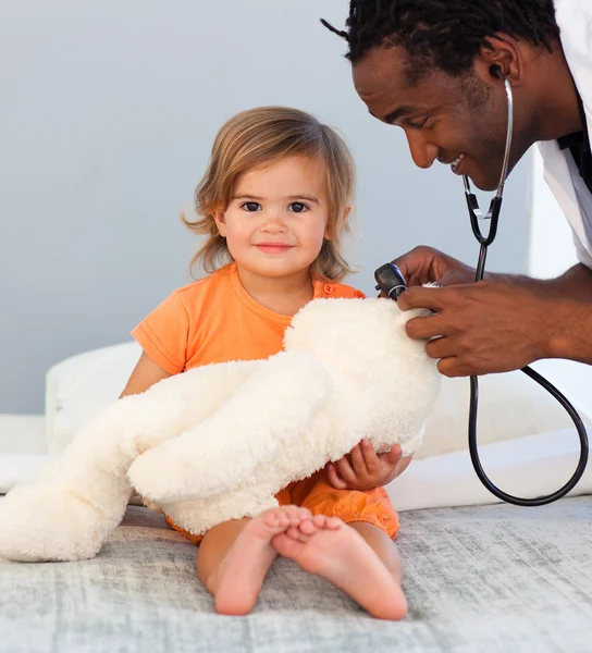 Детский врач осматривает маленькую девочку стетоскопом — стоковое фото
