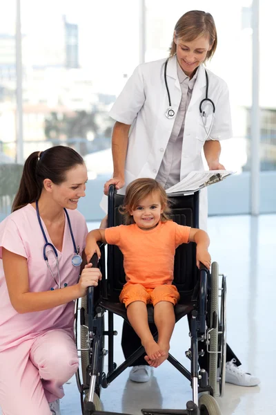 Doktorlar bir tekerlekli sandalye üzerinde oturan bir kız ile — Stok fotoğraf