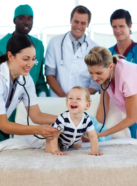 Bebê sorridente com uma equipe médica no hospital — Fotografia de Stock