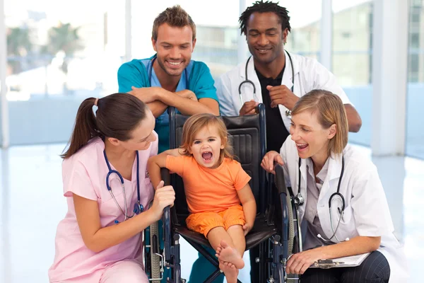 Doctors playing with a baby in a wheelchair — Stock Photo, Image