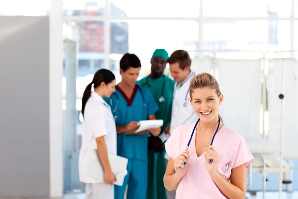 Jonge verpleegster met haar team in de achtergrond — Stockfoto