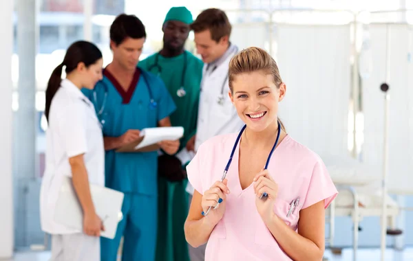 Portret uśmiechający się pielęgniarki z zespołem w tle — Zdjęcie stockowe