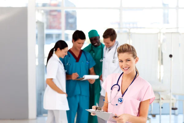 Schöne Krankenschwester mit ihrem Team im Hintergrund — Stockfoto