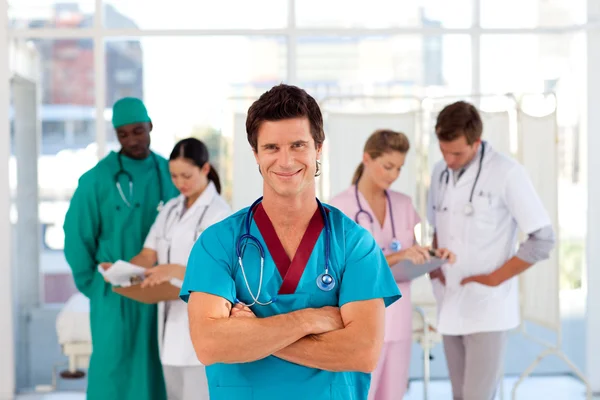 Médico sorridente com sua equipe em segundo plano — Fotografia de Stock