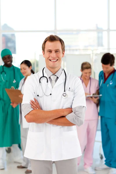 Jovem e sorridente médico com sua equipe em segundo plano — Fotografia de Stock