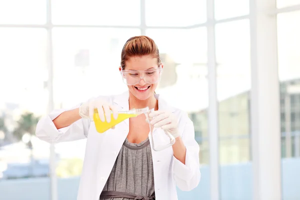 Cientista feminina sorridente examina um tubo de ensaio — Fotografia de Stock
