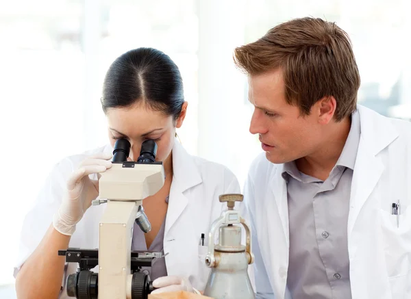 Científicos mirando a través de un microscopio — Foto de Stock