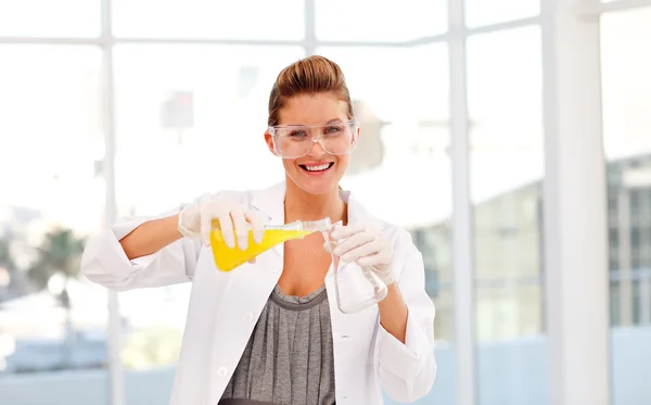 Attractive scientist examining a test-tube smiling at the camera — Stock Photo, Image