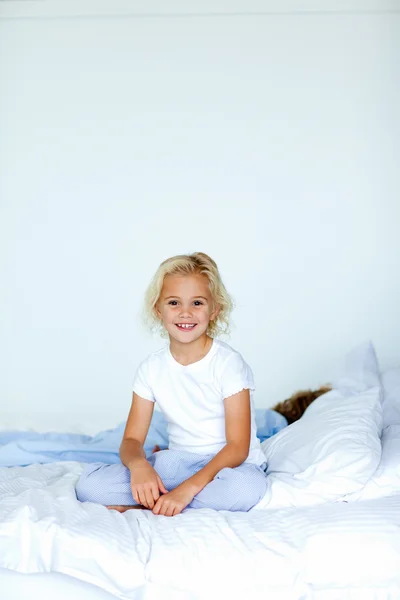 Malá dívka sedící v posteli s copyspace — Stock fotografie