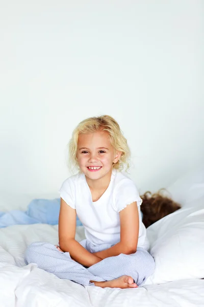 Klein meisje zitten in bed met copyspace — Stockfoto