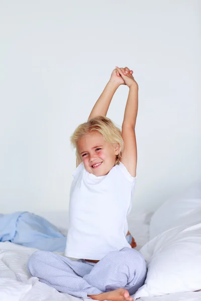 Blond meisje die zich uitstrekt in bed — Stockfoto
