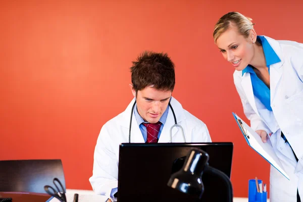 Lékaři pracující s přenosným počítačem v kanceláři — Stock fotografie