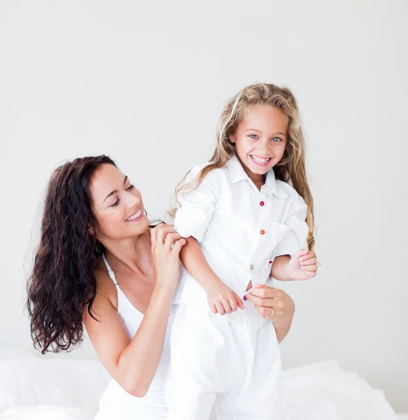 Beautiful mother and her daughter looking at the camera on the bed — Stock Photo, Image