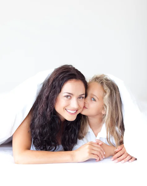 Vacker mor och hennes dotter tittar på kameran på sängen — Stockfoto