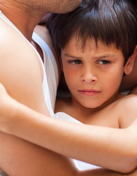 Upset child lying with his father in bed — Stock Photo, Image