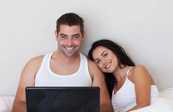 Pareja feliz usando un portátil en la cama —  Fotos de Stock