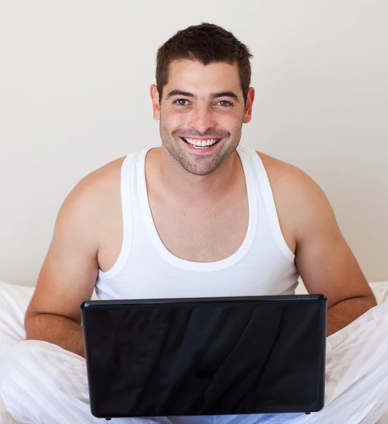 Szép ember használ a laptop az ágyon — Stock Fotó