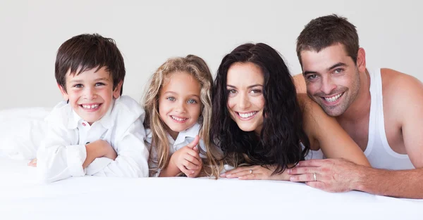 Familia alegre divirtiéndose juntos en la cama —  Fotos de Stock