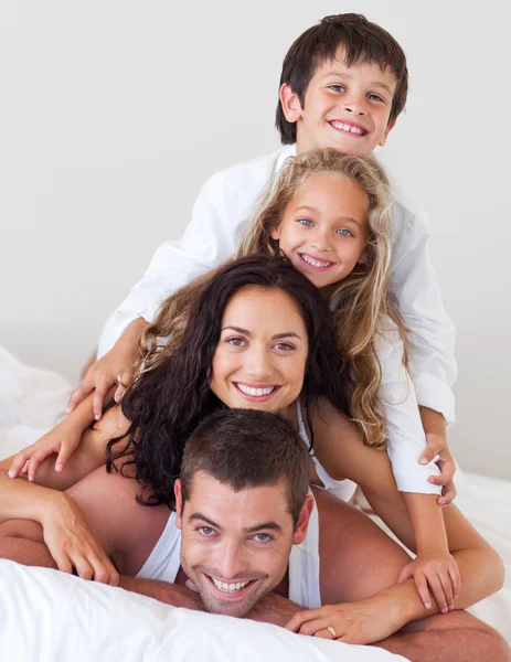 Familia alegre divirtiéndose juntos en la cama —  Fotos de Stock