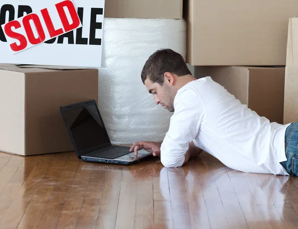 Hombre atractivo tirado en el suelo usando una computadora portátil —  Fotos de Stock
