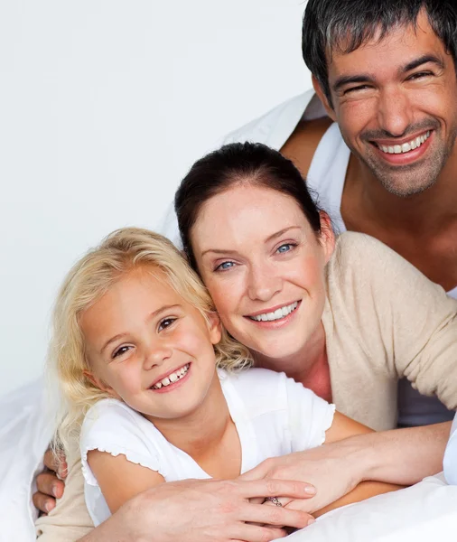 Föräldrar och dotter på säng ler mot kameran — Stockfoto