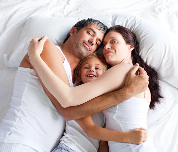 Weinig gril ontspannen op bed met haar ouders — Stockfoto