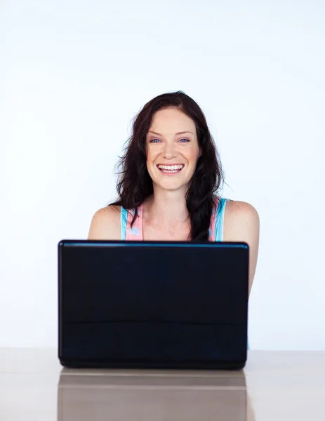 Жінка працює з ноутбуком, посміхаючись на камеру — стокове фото