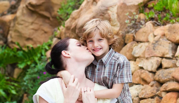 Mother kissing her son in a park — Stock Photo, Image