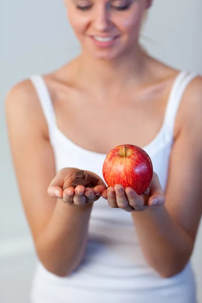 Beautiful woman holding chocolate and apple focus on apple — Stock Photo, Image