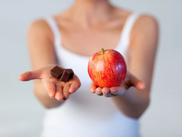 Close-up of woman showing chocolate and apple focus on apple — Stock Photo, Image