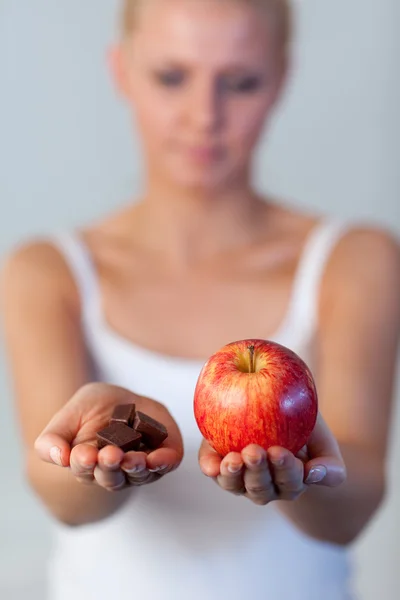 Portrait of awoman holding chocolate and apple focus on apple — Stock Photo, Image