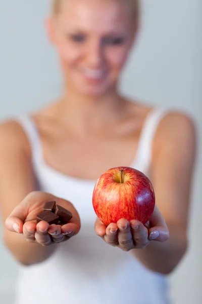 Красивая женщина держит шоколад и яблоко сосредоточиться на яблоко — стоковое фото