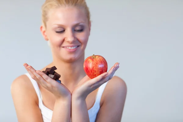 Beautiful woman showing chocolate and apple focus on chocolate and apple — Stock Photo, Image