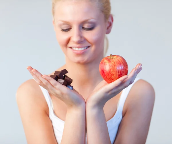 Junge Frau zeigt Schokolade und Apfel im Fokus — Stockfoto