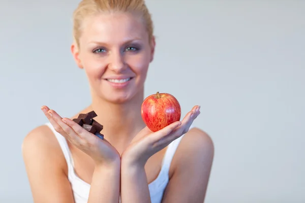 Attractive woman showing chocolate and apple focus on chocolate and apple — Stock Photo, Image
