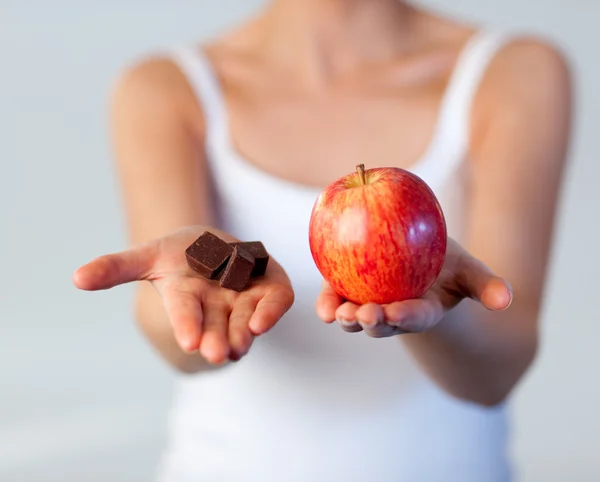 Beautiful woman showing chocolate and apple focus on chocolate — Stock Photo, Image