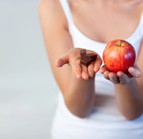 Женщина показывает шоколад и яблоко сосредоточиться на шоколаде — стоковое фото